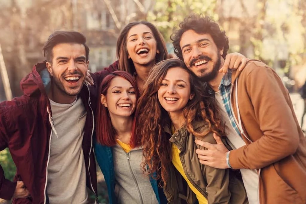 Laughing Friend Group Outdoors Group of five young friends laughing and hugging outdoors in casual clothes reminiscent of a sitcom friend group like New Girl or Friends