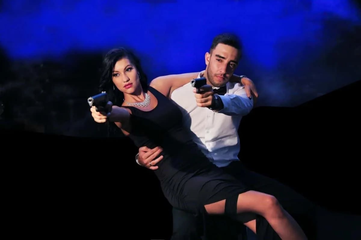 Sexy couple aiming guns passionately during intense action scene.