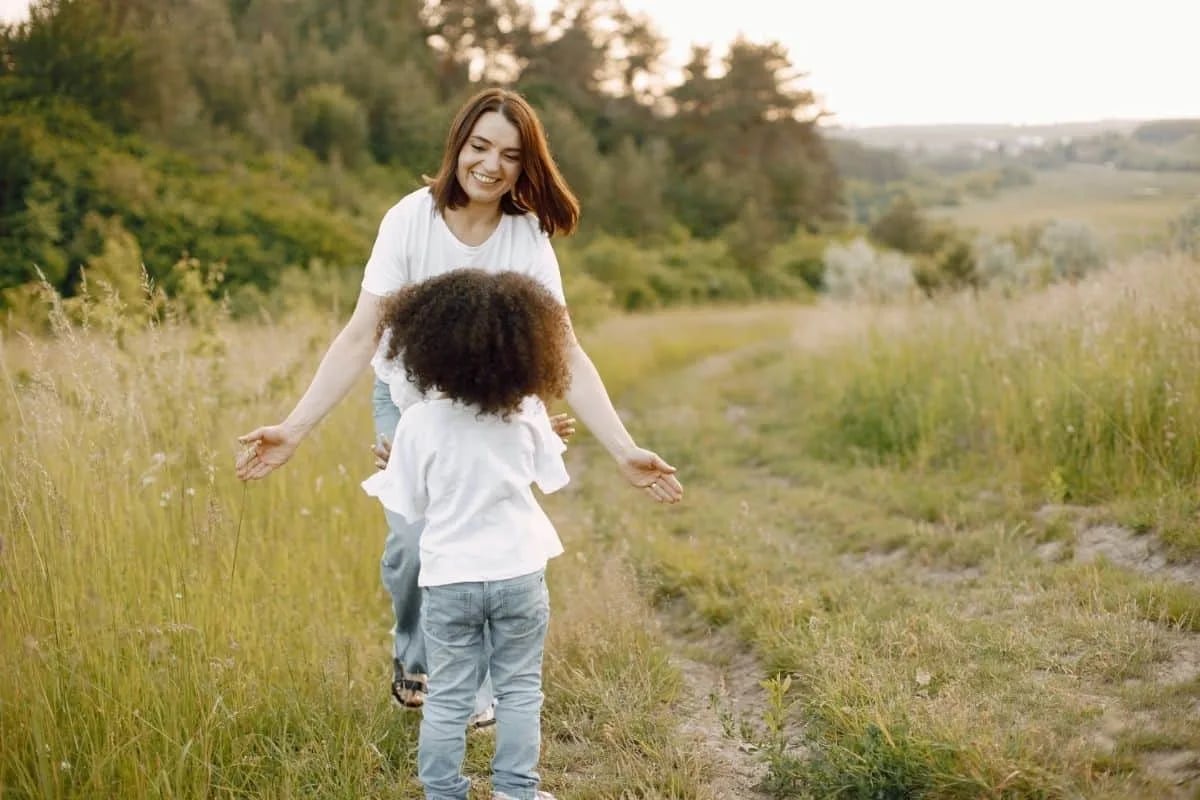 Mother and daughter sharing a joyful moment walking through a sunlit grassy field, reflecting the warm mother-daughter bond central to shows like Ginny and Georgia
