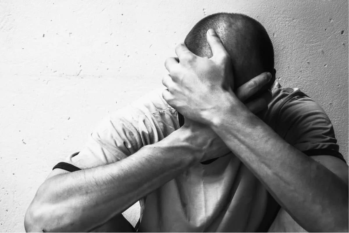 Man with hands on head expressing emotional pain illustrating the chaos of addiction in movies about heroin