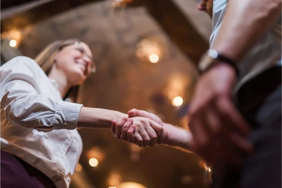 Close-up of two people shaking hands in a professional setting representing job motivation from movies about getting a job