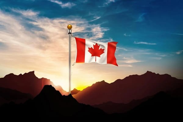 Flag of Canada waving on mountain at sunset, symbol of national pride and landscape beauty.