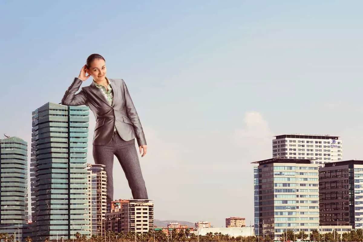 Businesswoman towering over city skyline, symbolizing leadership and success in the corporate world.