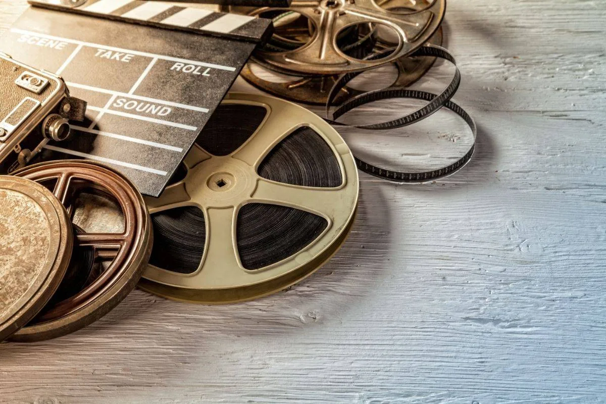 Old film reels and clapperboard used in filmmaking, vintage cinema equipment, and movie production gear.