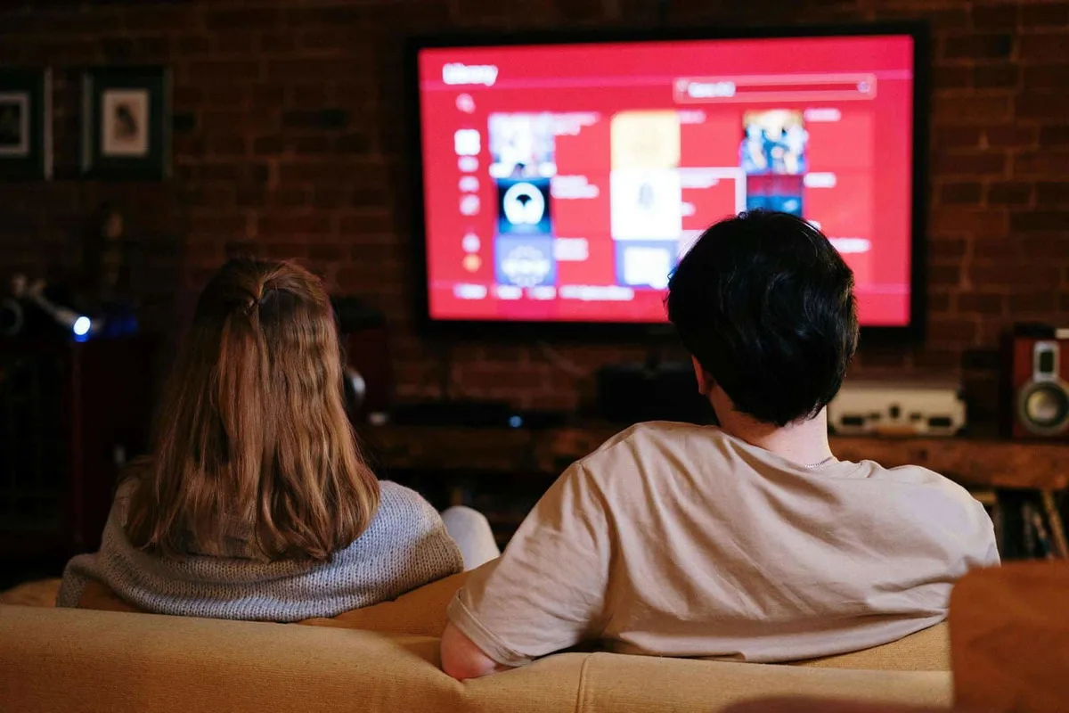 Young couple watching TV streaming service at home.