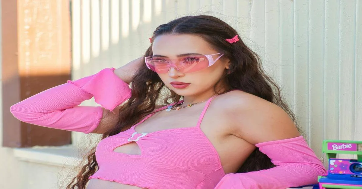 Stylish young woman in pink crop top with sunglasses and accessories, outdoor casual fashion look.