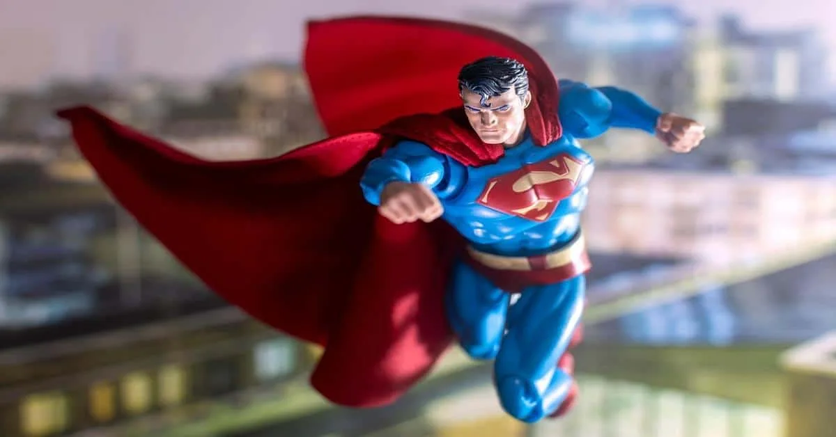 Detailed Superman figure soaring with red cape in city background.