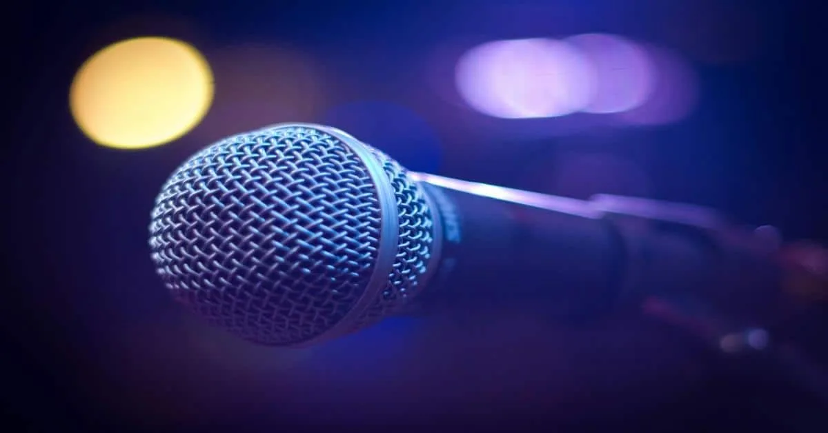 Close-up of a professional microphone with colorful bokeh lights in the background, ideal for TV shows or performances.