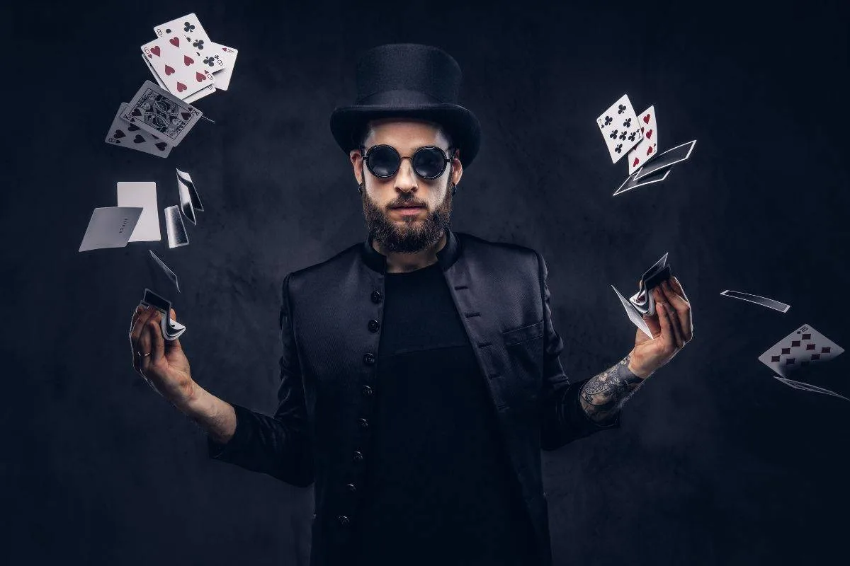 A stylish magician wearing dark sunglasses and a black top hat performing a card magic trick