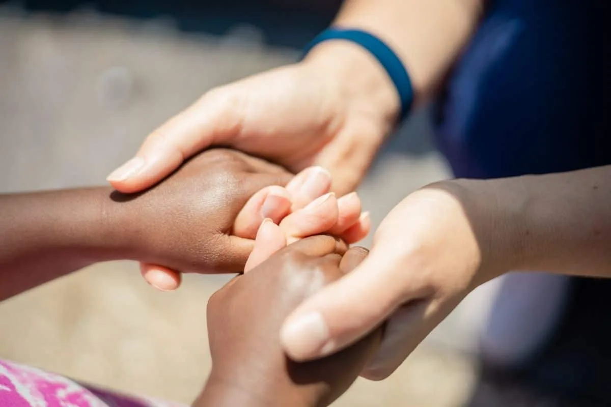 Close-up of diverse hands holding each other in unity symbolizing compassion and community support for orphaned protagonists in movies about orphans