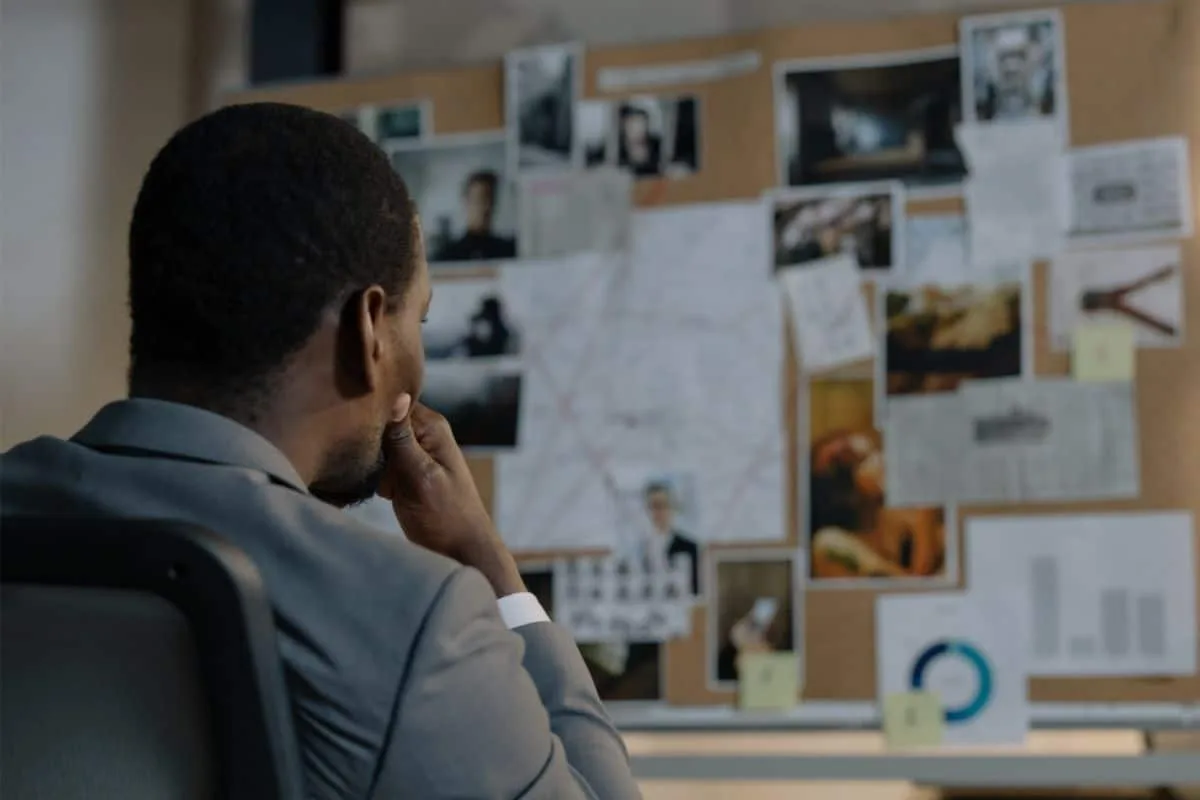 Close-up of man analyzing conspiracy board with photos and notes representing crime mystery shows like Broadchurch