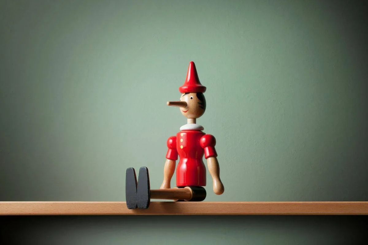 Wooden Pinocchio puppet with red hat on shelf representing iconic movies about toys